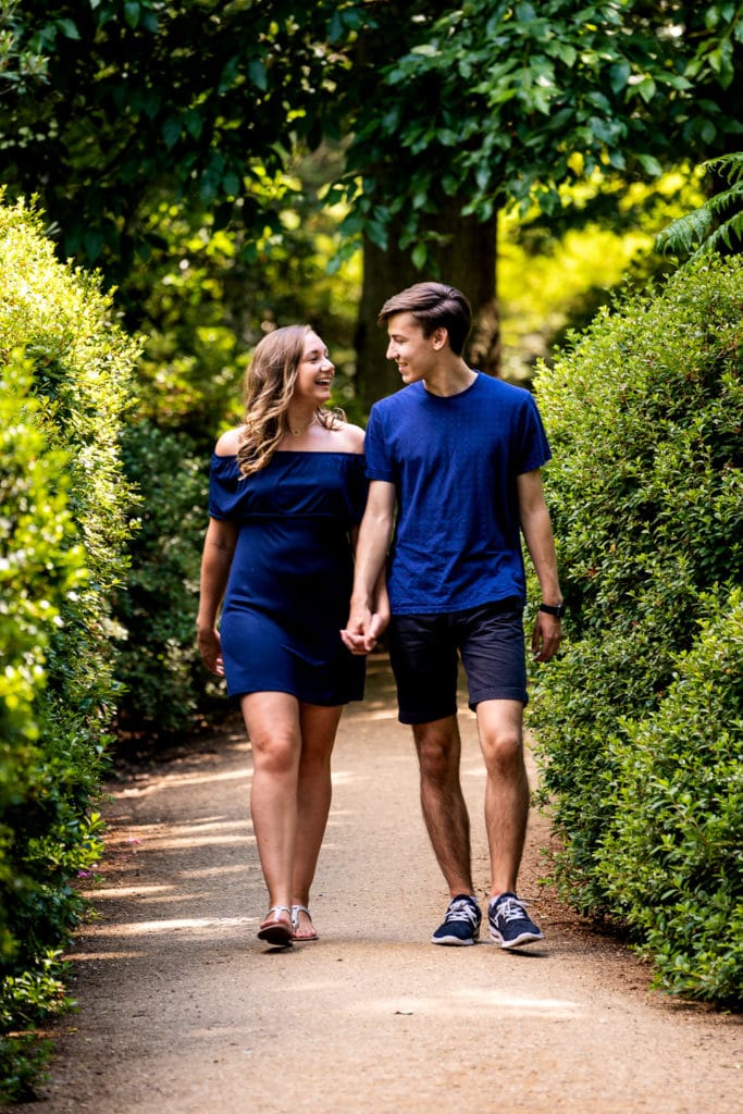 Couple walking through the beautiful surroundings of Richmond Park in Surrey smiling and chatting during their engagement photo shoot