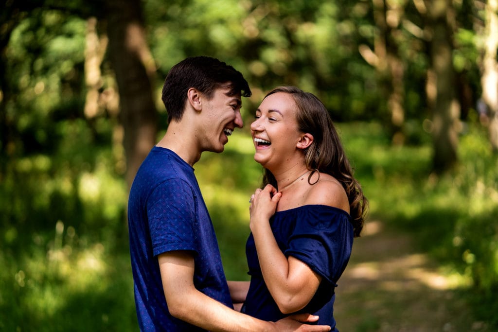 Smiling couple enjoying themselves under the trees pre wed photo shoot in the ever popular Richmond Park Surrey