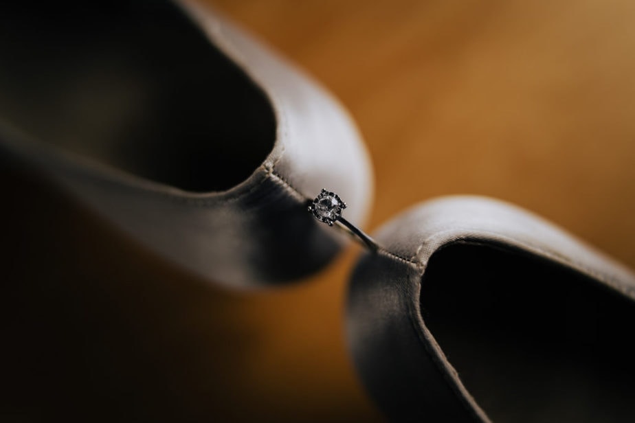 creative shot of wedding rings and brides shoes