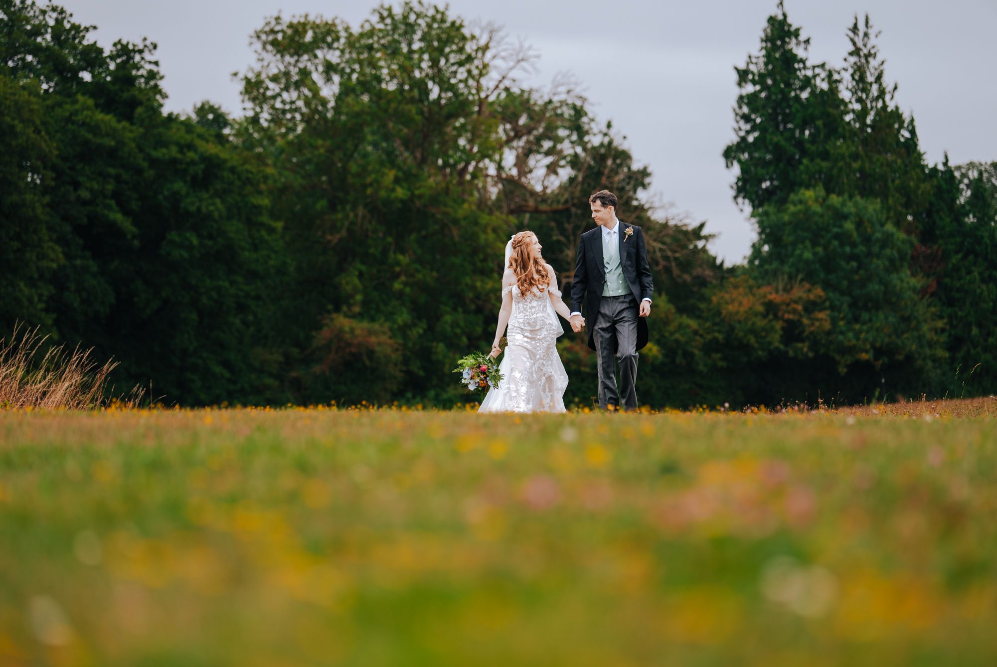 Bride and groom walking together outdoors during a UK wedding, with the landscape around them