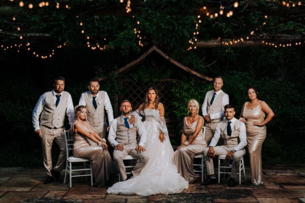 Wedding party group portrait at night under fairy lights created by Alex Buckland Photography