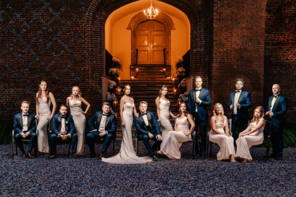 Wedding party seated outside a grand entrance in a classic editorial group pose
