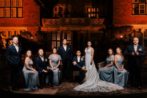 Creative wedding group portrait outside a historic venue captured with rich warm tones